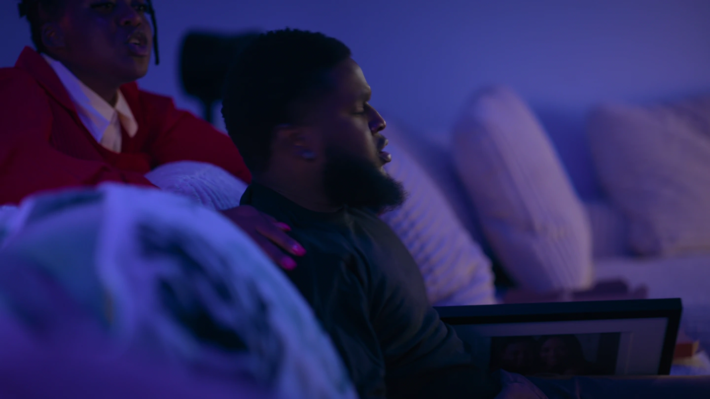 The woman in red leaning over the back of the sofa, close to his shoulder.