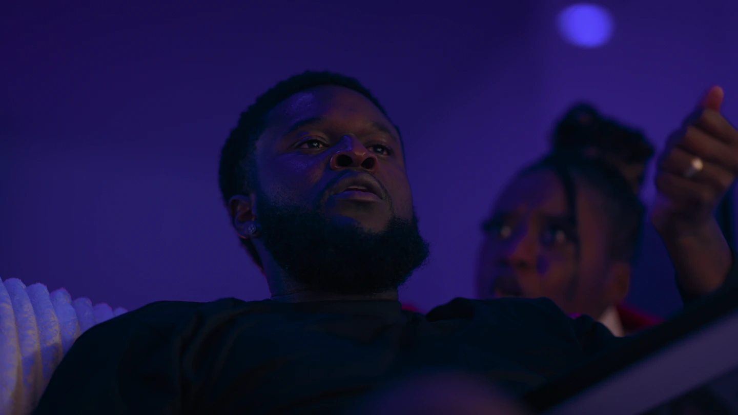 A low angle: the man looking up and past the camera, her face at his shoulder.